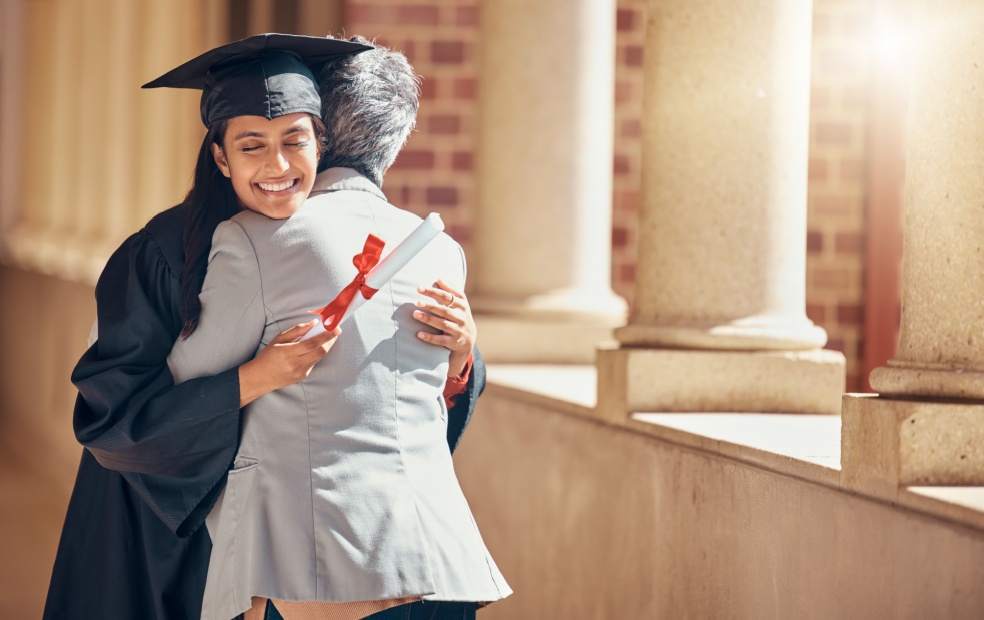A college graduate being hugged by their family.