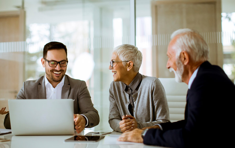 Financial advisor reviewing financial information on a laptop with two clients during an in-person planning meeting, demonstrating collaboration, communication, and client engagement.
